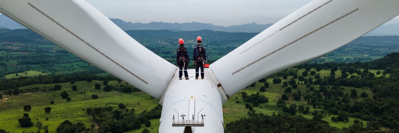 Couple standing on top of a wind turbine