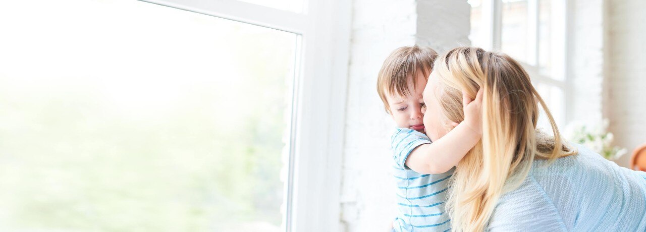 Mother and young son at home by a window.