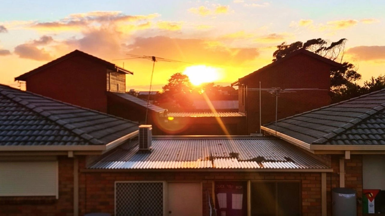 sun setting behind houses