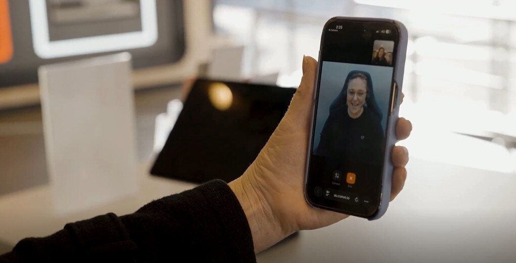 hand holding mobile phone with woman on screen